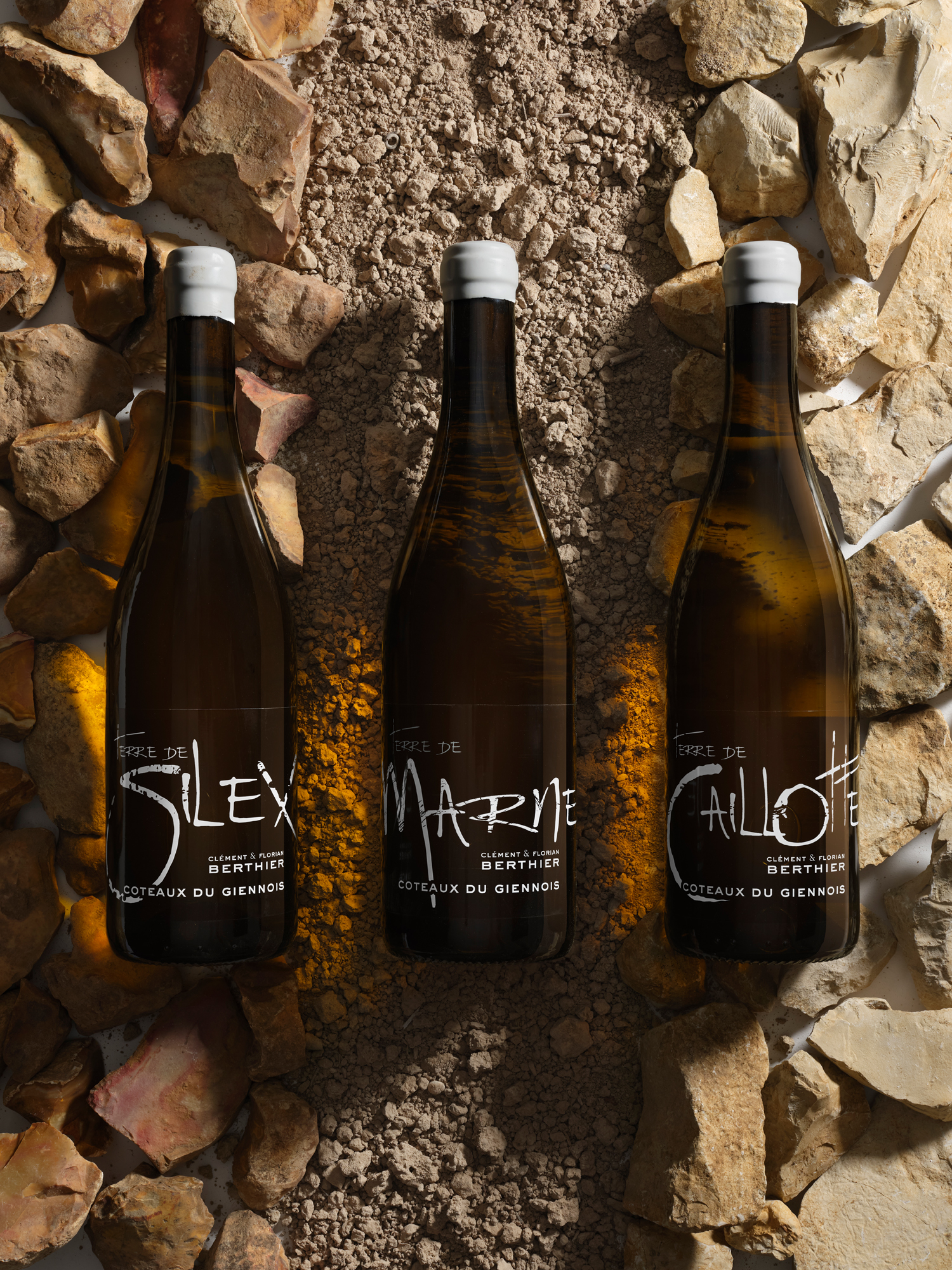Les trois bouteilles Terre de Marne, Terre de Caillotte et Terre de Silex posées par terre sur un carrelage mouillé